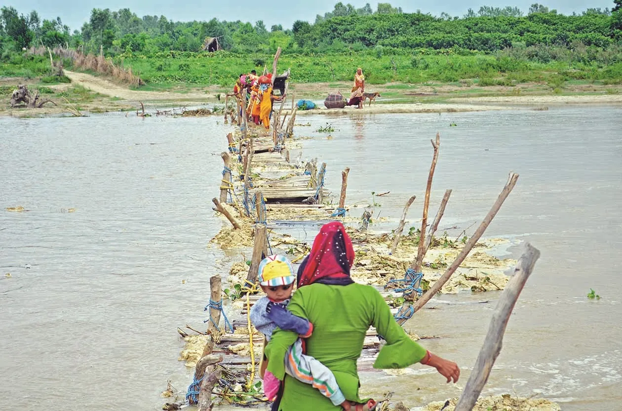 बच्चे को लेकर पुल पार करती महिला।