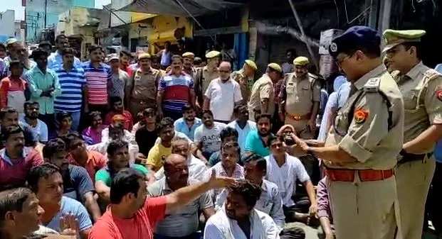बदायूं: पालिका टीम से नोकझोंक के बाद सड़क पर बैठे व्यापारी, नारेबाजी