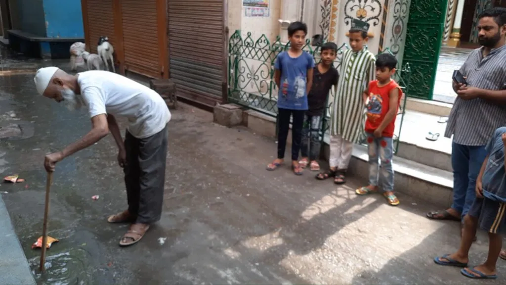 मस्जिद के सामने बहते गंदे नाले व सीवर लाइन की खुद ही सफाई करते स्थानीय लोग