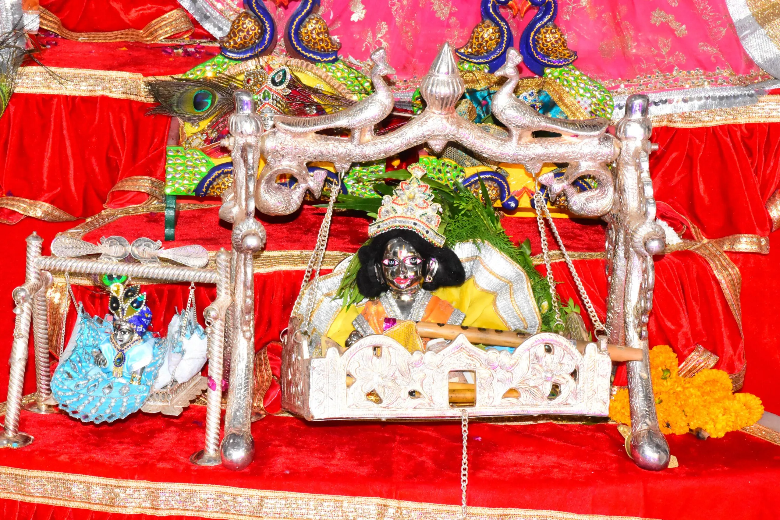 राधा-कृष्ण मंदिर में चांदी के पालने में झूला झूलते लड्डू गोपाल।
