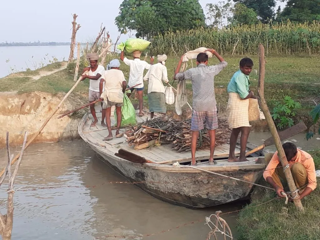 नाव से चूल्हा जलाने के लिए लकड़ियां लाते ग्रामीण